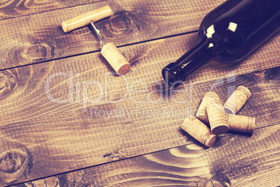 Bottle of wine with corkscrew on wooden background