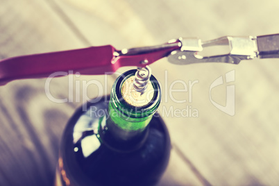 Bottle of wine with corkscrew on wooden background