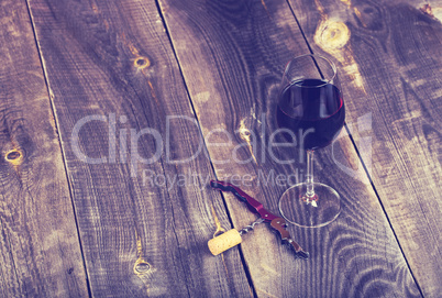 Pouring red wine into the glass against wooden background