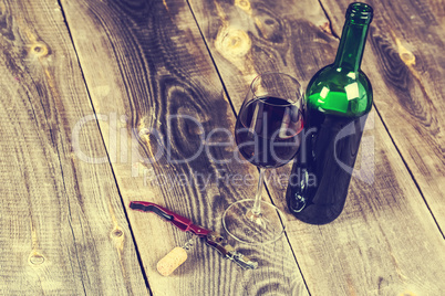 Pouring red wine into the glass against wooden background