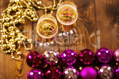 Two Glasses With Champagne and Christmas Tree Decorations on the table.