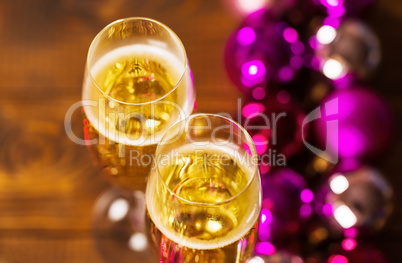 Two Glasses With Champagne and Christmas Tree Decorations on the table.