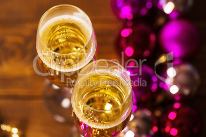 Two Glasses With Champagne and Christmas Tree Decorations on the table.