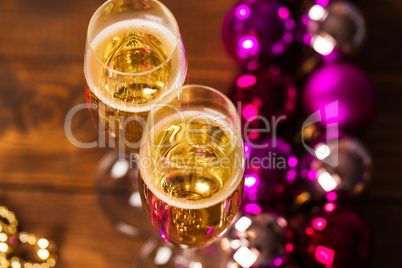 Two Glasses With Champagne and Christmas Tree Decorations on the table.