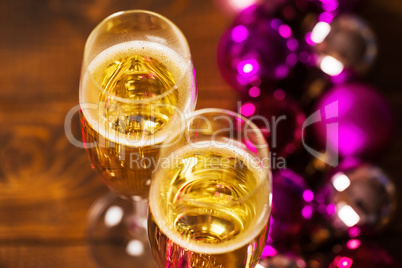 Two Glasses With Champagne and Christmas Tree Decorations on the table.