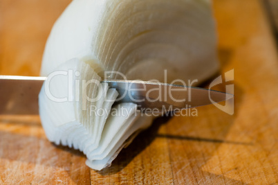 Macro of knife cutting through white onion layers