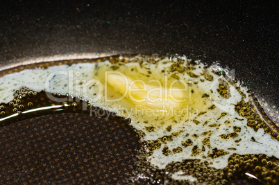 Macro of piece of butter melting in pan