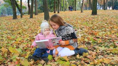 little sisters read the book in the autumn park