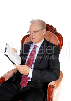 Mature man in suit reading book.