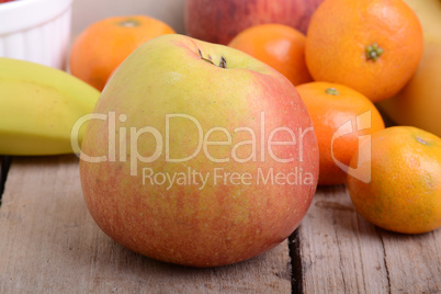 Bananas apple mandarin peach strawberry on wooden background as health food concept