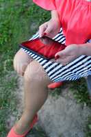 The girl in the red dress sitting on a bench  with tablet