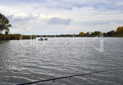 Water landscape with a fisherman in a boat on the lake and cloud