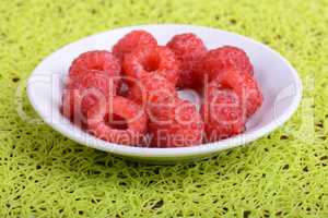Fresh raspberries. Closeup of fruits on a white plate