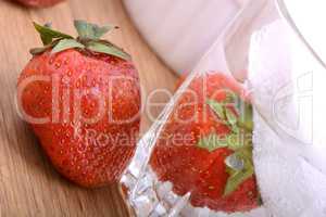 Strawberry on wooden plate and strawberry frozen with ice in cup