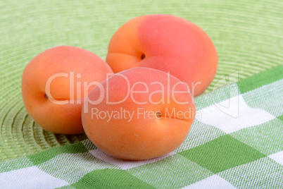 Full peaches close up on green material background.