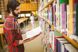 Hipster student picking a book in library