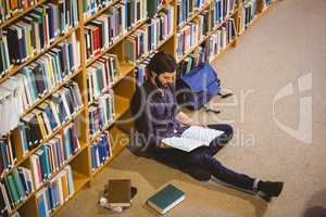 Student reading book in library on floor