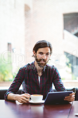Hipster student using tablet in canteen