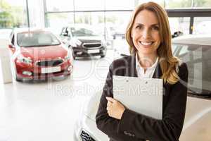 Smiling saleswoman holding document while looking at camera