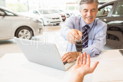 Smiling salesman holding a customer car key