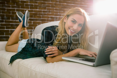 Pretty blonde relaxing on the couch using laptop