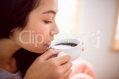 Asian woman relaxing on couch with coffee