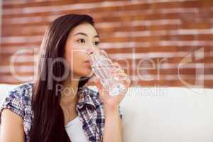 Asian woman on the couch drinking water