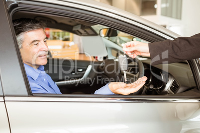 Salesman giving keys to a smiling businessman