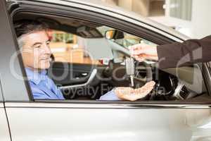 Salesman giving keys to a smiling businessman
