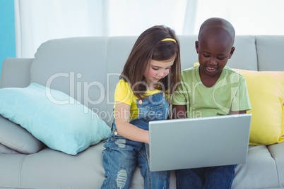 Smiling girl and boy using a laptop