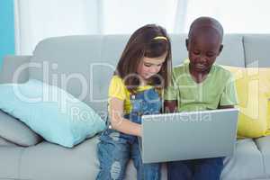 Smiling girl and boy using a laptop