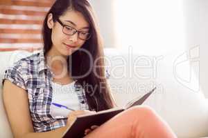 Asian woman on the couch writing