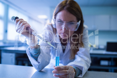 Scientist syringing chemical into test tube