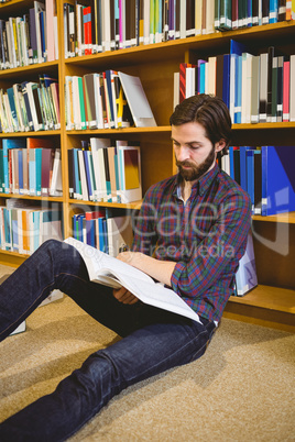 Student reading book in library on floor