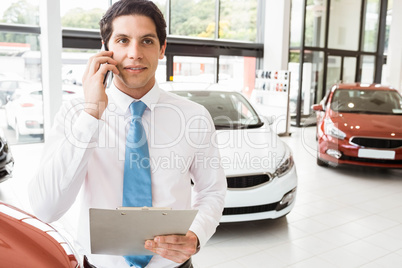 Smiling businessman on the phone holding clipboard