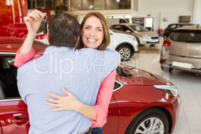 Smiling woman holding key while hugging her husband