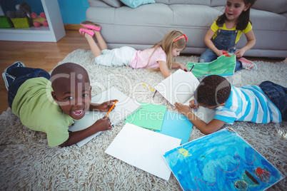 Smiling kids drawing pictures on paper