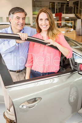 Smiling couple leaning on car