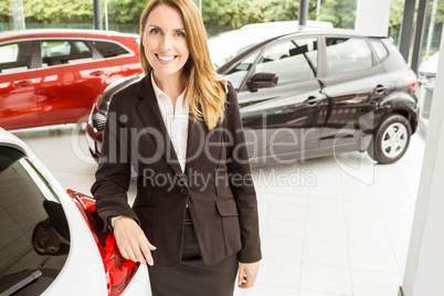 Smiling saleswoman standing against a car