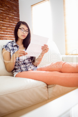 Asian woman on the couch reading letter