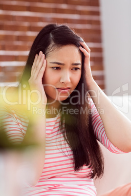 Asian woman getting headache on couch