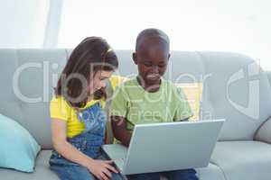 Smiling girl and boy using a laptop