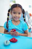 Smiling girl using modelling clay