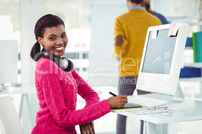 Creative businesswoman wearing headphones at her desk