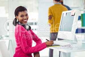 Creative businesswoman wearing headphones at her desk