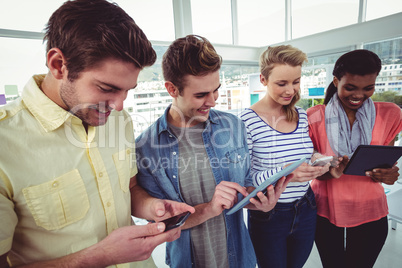 Smiling creative team standing in a line using technology