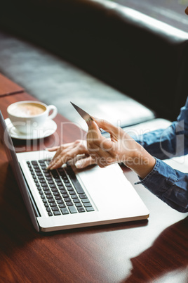 Student using laptop in cafe to shop online