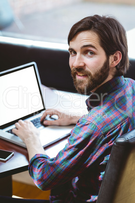 Hipster student using laptop in canteen