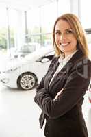 Smiling saleswoman standing with arms crossed