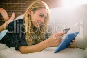 Pretty blonde relaxing on the couch using tablet